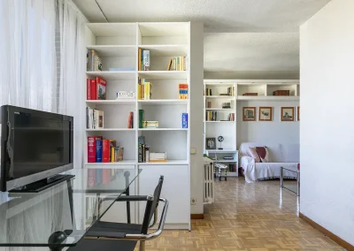 Imagen del salón con zona de estudio y sofá, destacando el trabajo realizado en las estanterías con una ordenación y vaciado que maximiza el espacio y su funcionalidad