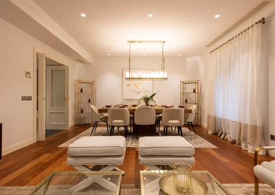 Salón de vivienda de lujo en Barrio Salamanca, con suelos oscuros, mobiliario neutro y comedor para 8 personas, decorado para atraer a ejecutivos de alto standing.