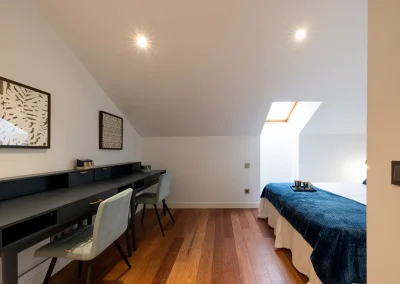 Home Staging en un ático dúplex de lujo en Calle de Serrano, Madrid, mostrando doble escritorio de Maisons du Monde, sillas verde aguamarina y parte de una cama en el entorno elegante y funcional.