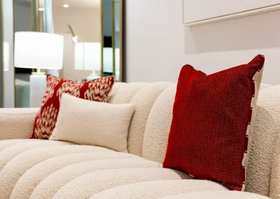 Cojines burdeos Gancedo sobre sofá tapizado en bouclé blanco, en proyecto de home staging para vivienda de lujo en Madrid.